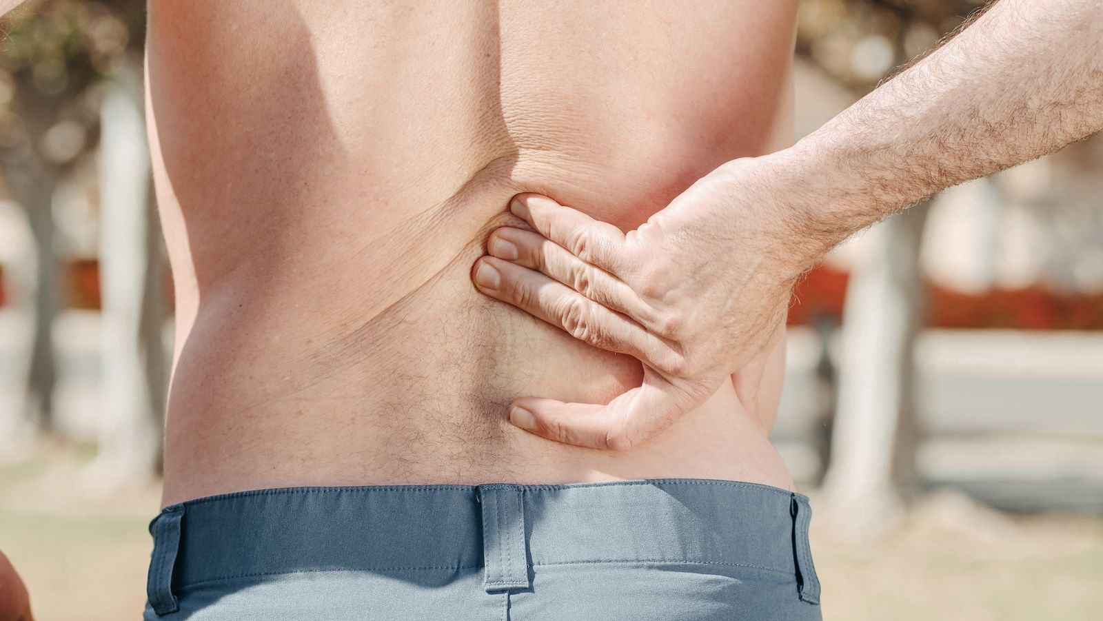 A man holding his lower back in discomfort