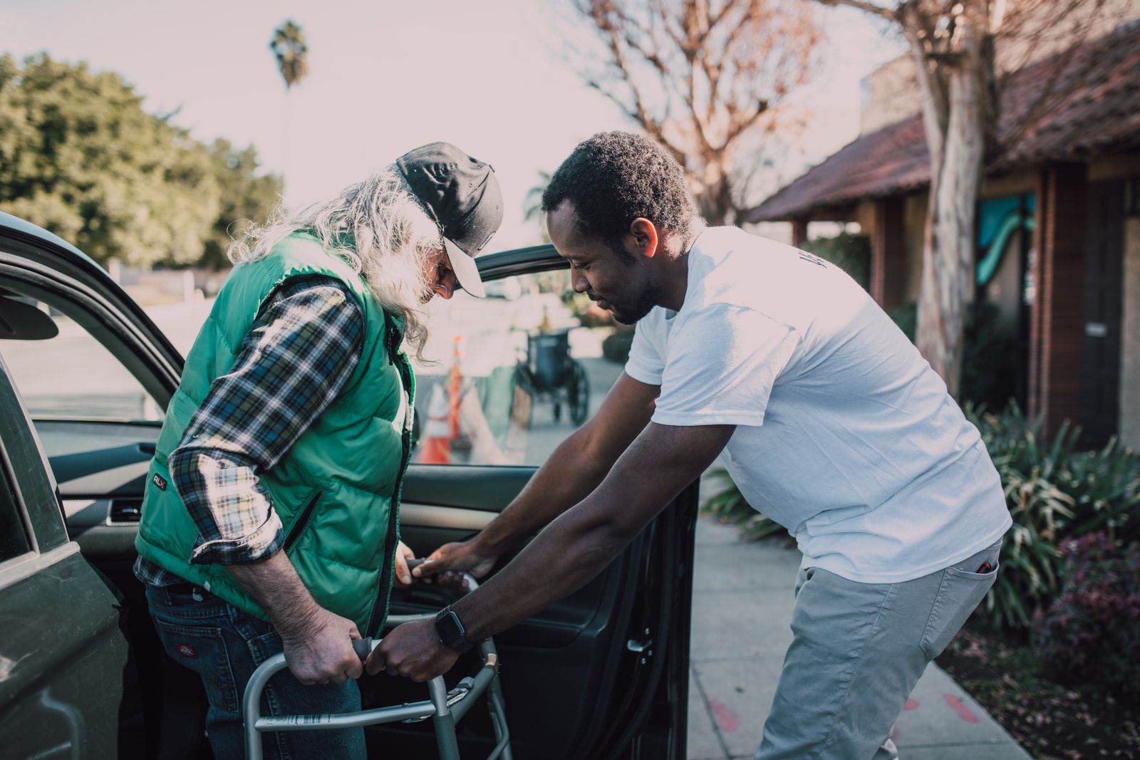 Carer helping an elderly man walk with a walking frame