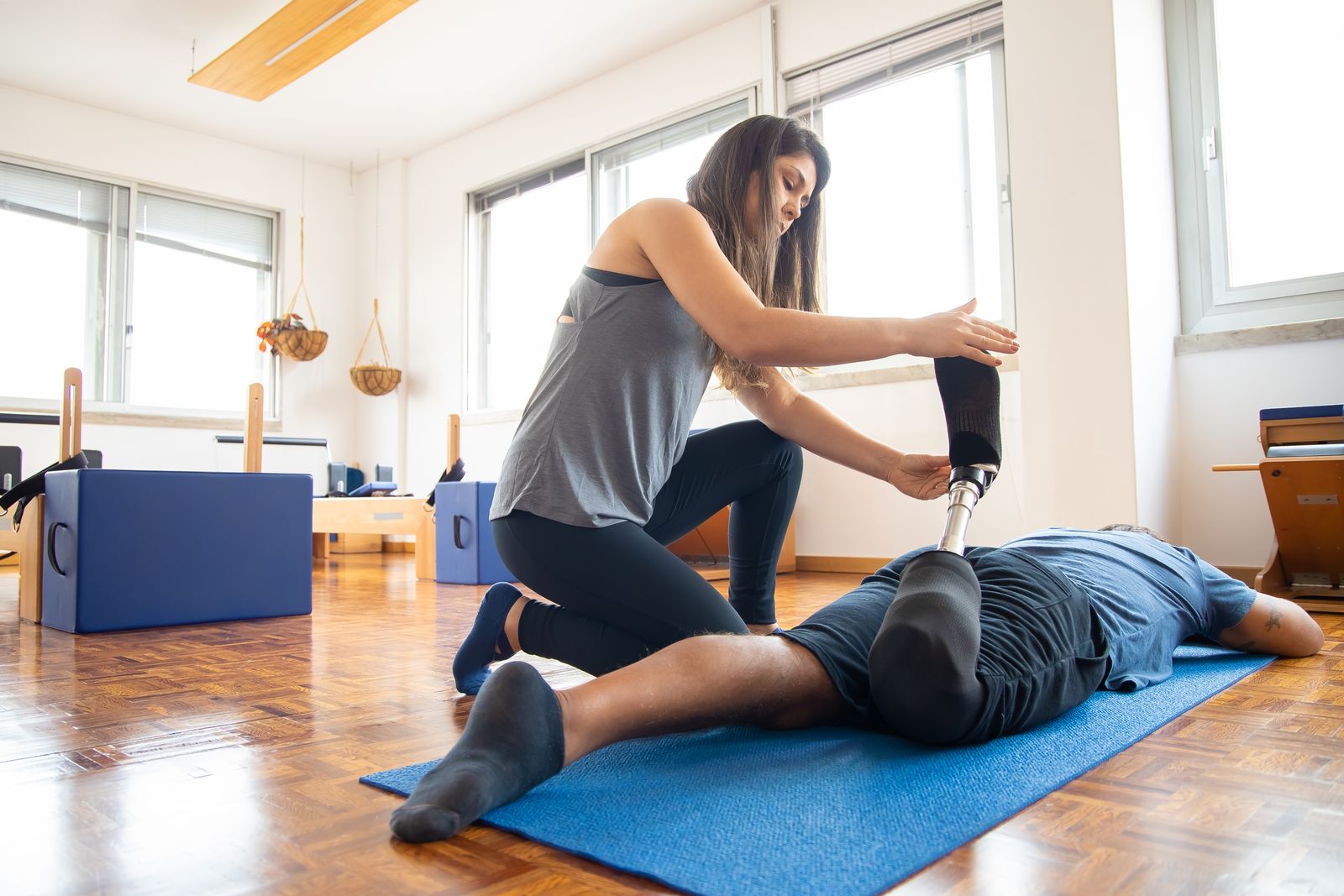 Physiotherapist guiding a rehabilitation exercise on a mat at home